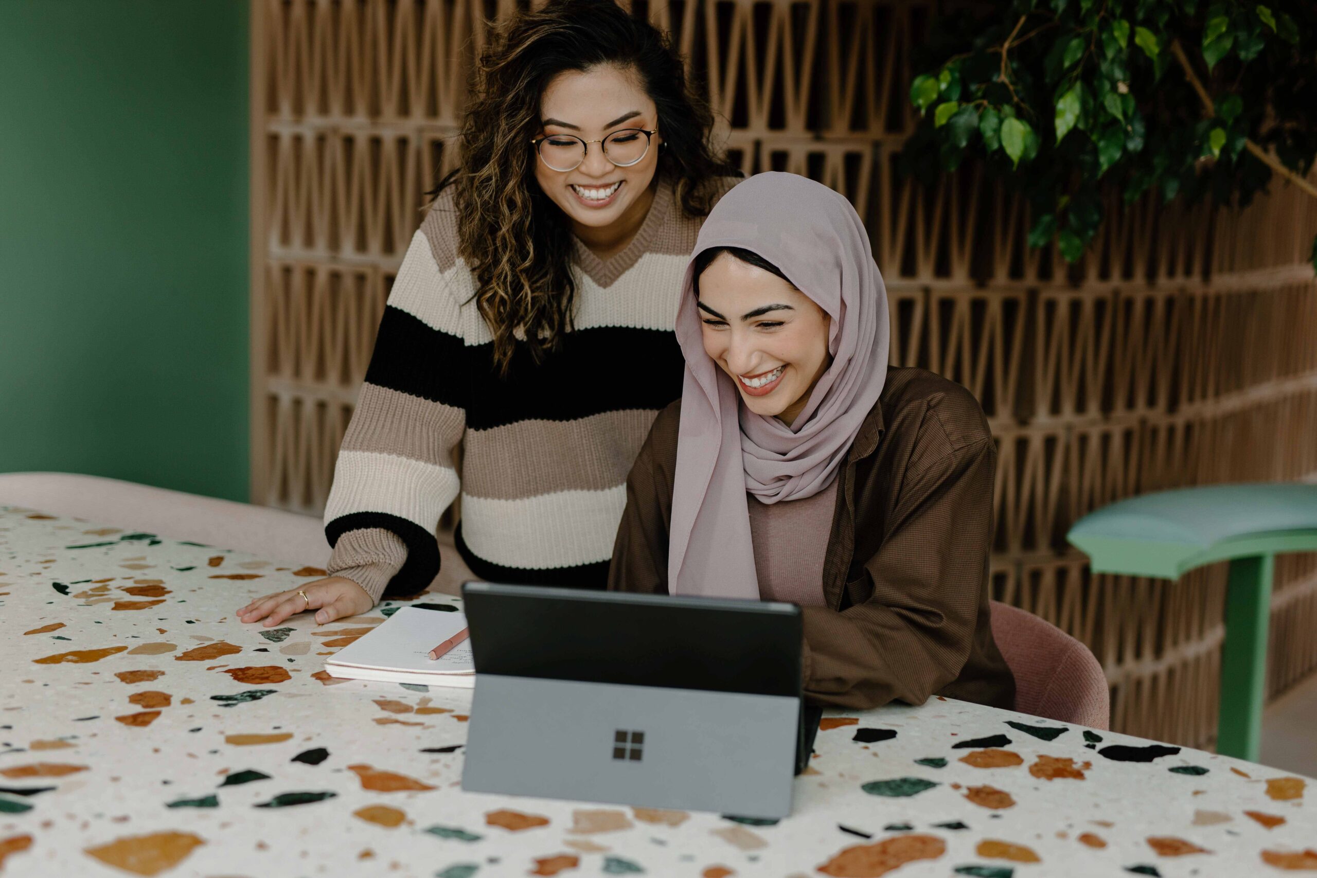 Female colleagues smiling looking at laptop together